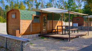 Une cabane en bois dotée d’un patio couvert, de murs en pierre et d’un sol en gravier.
