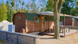 Une petite cabane en bois dotée d’un porche abrité, de murs en pierre et d’une table de pique-nique.