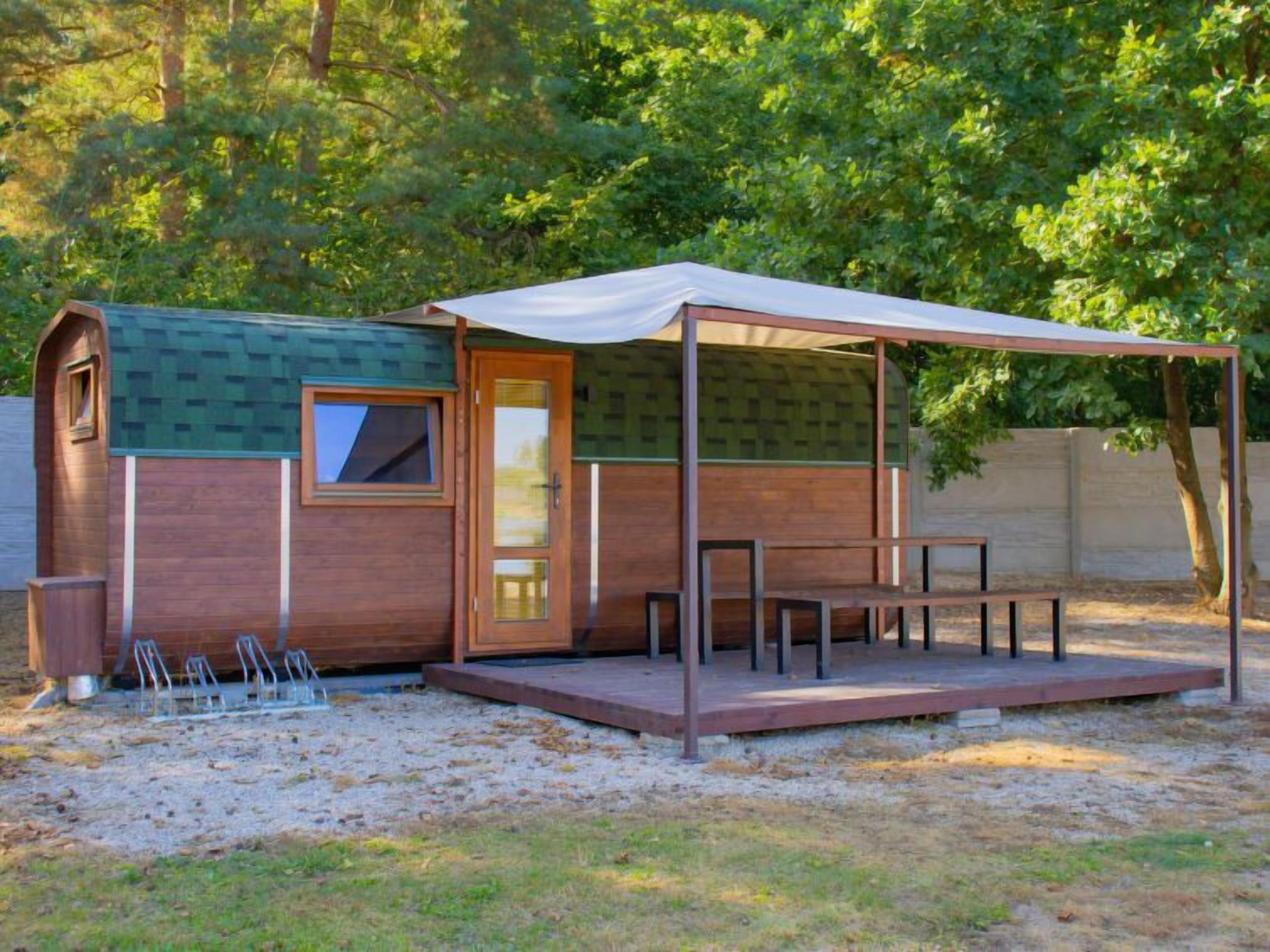 A small wooden cabin with a covered patio, a door, and a window.