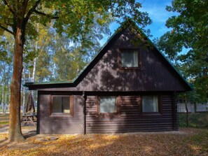 Rustic cabin-style building with a steeply pitched roof and symmetrical facade, featuring evenly spaced windows.