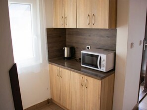 Kitchen area with wooden cabinetry, stainless steel appliances, and a tiled floor.