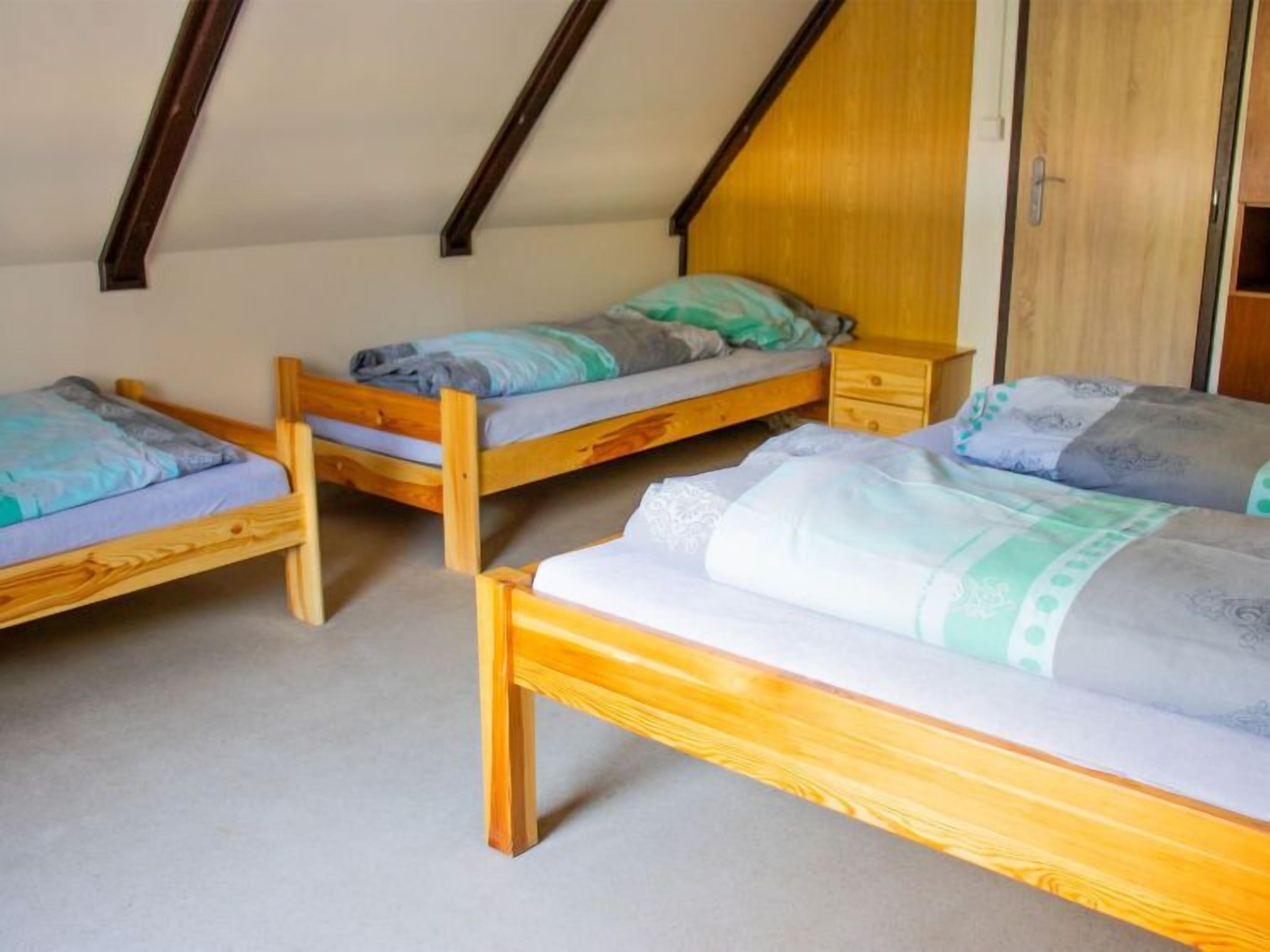 Un dormitorio con tres literas de madera, cada una con una mesita de noche y un cajón.