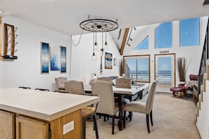 Enjoy meals with a view of the ocean from this dining area featuring a long table and comfortable seating.