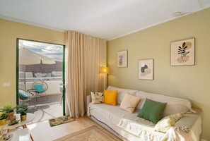 A living room with a sofa, a chair, a lamp, and a view of the outside. - Zen House Holiday Home with Sea View, Communal Pool, and Wi-Fi (Puerto Rico)