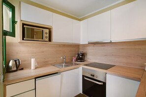 A compact kitchen with a microwave, sink, stove, and dishwasher. - Zen House Holiday Home with Sea View, Communal Pool, and Wi-Fi (Puerto Rico)