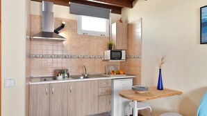Une cuisine de taille réduite, équipée d’un four à micro-ondes, d’un évier et de meubles de rangement en bois.