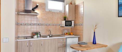 Una cocina compacta con microondas, fregadero y armarios de madera.