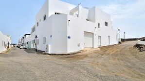 A white building with a garage door, a street, and a clear sky.