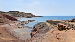Un paisaje costero con terreno rocoso, cielo despejado y vista al mar.