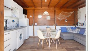 Una cocina funcional con lavadora, mesa de comedor con sillas y un sofá.