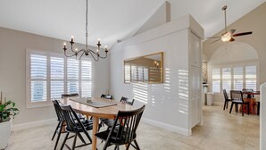 A dining area with a large wooden table, black chairs, a chandelier, and a ceiling fan. - Family Retreat: Pool & Fun Casita with Games (Las Vegas)