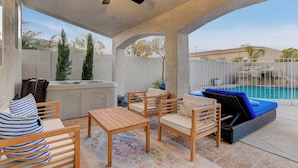 A covered outdoor patio with a pool, wooden furniture, and a ceiling fan. - Family Retreat: Pool & Fun Casita with Games (Las Vegas)