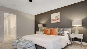 A bedroom with a bed, two nightstands, a lamp, and a painting on the wall. - Family Retreat: Pool & Fun Casita with Games (Las Vegas)