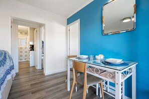 Une pièce comprenant une table à manger, des chaises, un lit et un mur bleu.