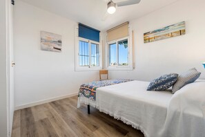 A bedroom with a bed, a chair, a window, and a ceiling fan. - Apartment "Paul" with Private Terrace and Wi-Fi (Torredembarra)