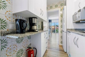 A kitchen with white cabinets, a coffee maker, a microwave, and a fire extinguisher. - Apartment "Paul" with Private Terrace and Wi-Fi (Torredembarra)