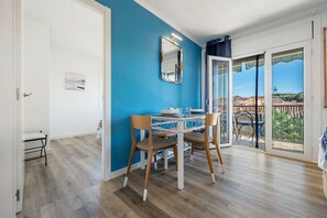 A dining area with a table and chairs, a mirror on the wall, and a view through a glass door. - Apartment "Paul" with Private Terrace and Wi-Fi (Torredembarra)