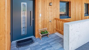 A wooden exterior with a dark door, a small bench with a plant, and a window. - Group accommodation in panoramic location (Mittersill)