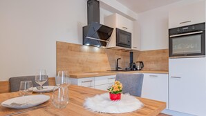 A modern kitchen with white cabinets, a microwave, and an oven. - Group accommodation in panoramic location (Mittersill)