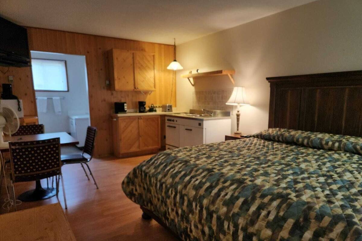 A compact room with a bed, a small kitchenette, a dining area, and a window.
