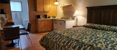 Une pièce de taille modeste comprenant un lit, une petite kitchenette, un coin repas et une fenêtre.