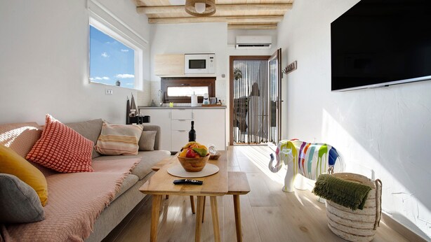 A modern living room with a sofa, a coffee table, a TV, and a kitchen in the background. - Studio 'Apartment La Higuera' with Sea View, Wi-Fi, and Air Conditioning (Arrecife)