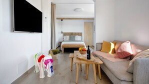 A modern room with a bed, a sofa, a TV, a wooden table, and a small stool. - Studio 'Apartment La Higuera' with Sea View, Wi-Fi, and Air Conditioning (Arrecife)