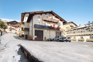 Un immeuble à plusieurs étages doté de balcons, d’un garage et situé dans une rue enneigée.