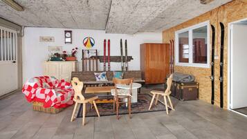 Ein gemütliches Wohnzimmer mit einer Couch, Sesseln, einem Holzschrank, Skiern und einer Wanduhr.