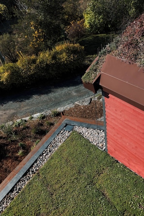 A rooftop garden with a red building, a gravel pathway, and surrounding vegetation.