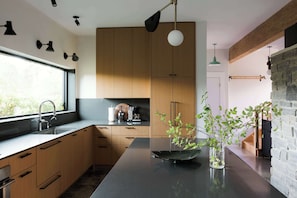 Una cocina moderna con armarios de madera, encimera negra y una isla central con un florero de plantas verdes.