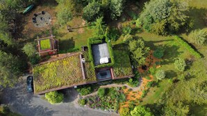 An aerial view of a property with a green roof, a swimming pool, and a garden area. - Starbase - Waterfront Home w Pickleball Court (Prince Edward)