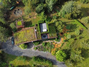 Vista aérea de uma propriedade com telhado verde, piscina e área de jardim.