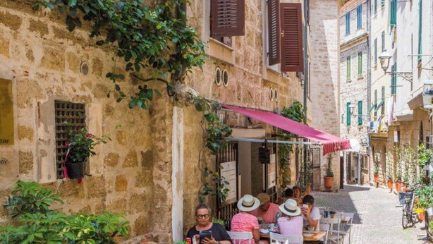 A narrow cobblestone street with outdoor seating at a café, stone buildings, and greenery. - Apartment "Blu Verdone" with Sea View, Balcony & Wi-Fi (algehro)