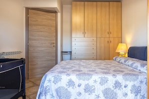 Une chambre à coucher avec un lit, une armoire en bois, une chaise et une table de chevet avec une lampe.