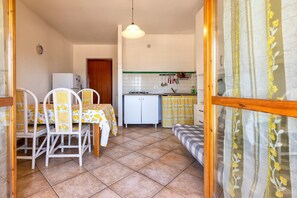 A compact kitchen with a dining area, a refrigerator, a sink, and a stove.