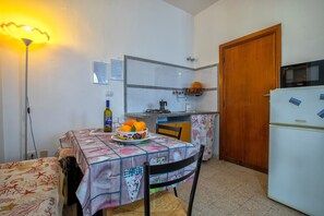 A compact kitchen with a dining table, chairs, a refrigerator, and a microwave. - Apartment "Lilla" with Sea View, Private Terrace and Wi-Fi (alghero)