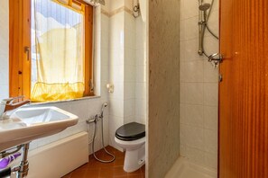 A bathroom with a sink, toilet, shower, and a window with a curtain. - Apartment "Lilla" with Sea View, Private Terrace and Wi-Fi (alghero)