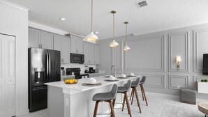 A modern kitchen with a central island, bar stools, pendant lighting, and a microwave. - Chic Retreat - Unforgettable Stay (Kissimmee)