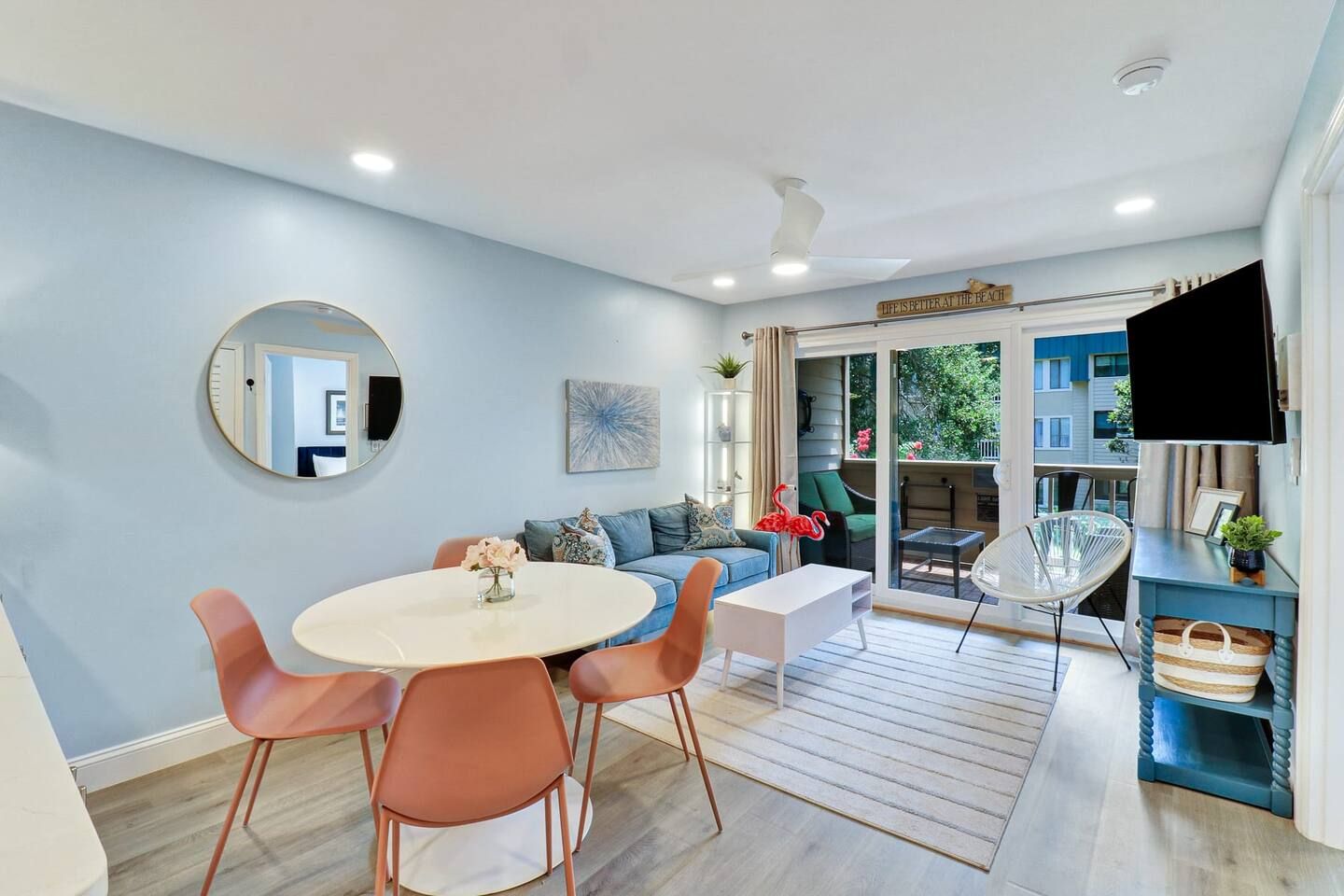 Een moderne woonkamer met een ronde tafel, oranje stoelen, een bank en een televisie.