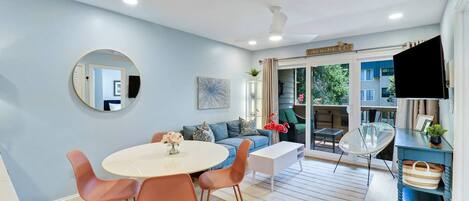 Een moderne woonkamer met een ronde tafel, oranje stoelen, een bank en een televisie.