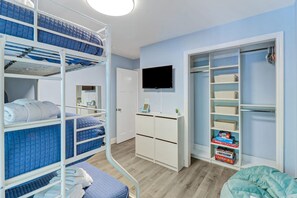 Habitación con literas, televisor, armario y unidad de almacenamiento.