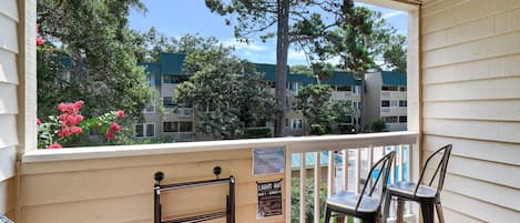 Un balcon donnant sur un quartier résidentiel, une chaise en osier et une chaise en métal.