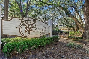 A wooden sign with 'The Foa On Port Royal Sound' written on it, surrounded by trees and shrubs. - Stunning 2 Bedroom Villa Steps to the Beach (Hilton Head Island)