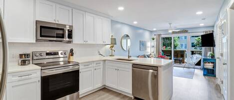 A modern kitchen with white cabinetry, stainless steel appliances, and a central island.