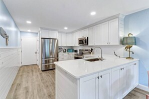 Una cocina moderna con armarios blancos, electrodomésticos de acero inoxidable y una isla central con fregadero.