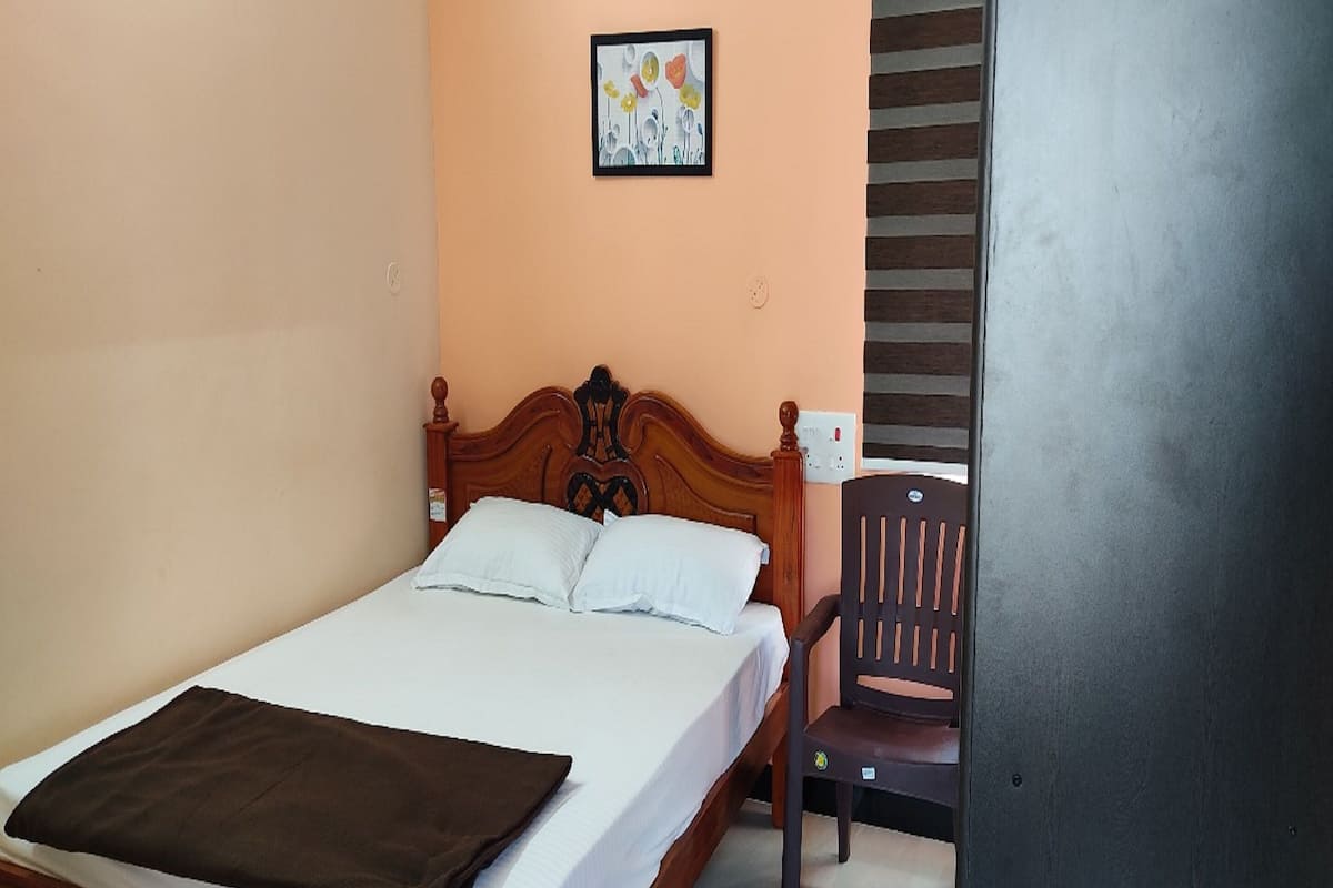 A neatly made bed with a brown blanket, a wooden headboard, and a chair beside it.