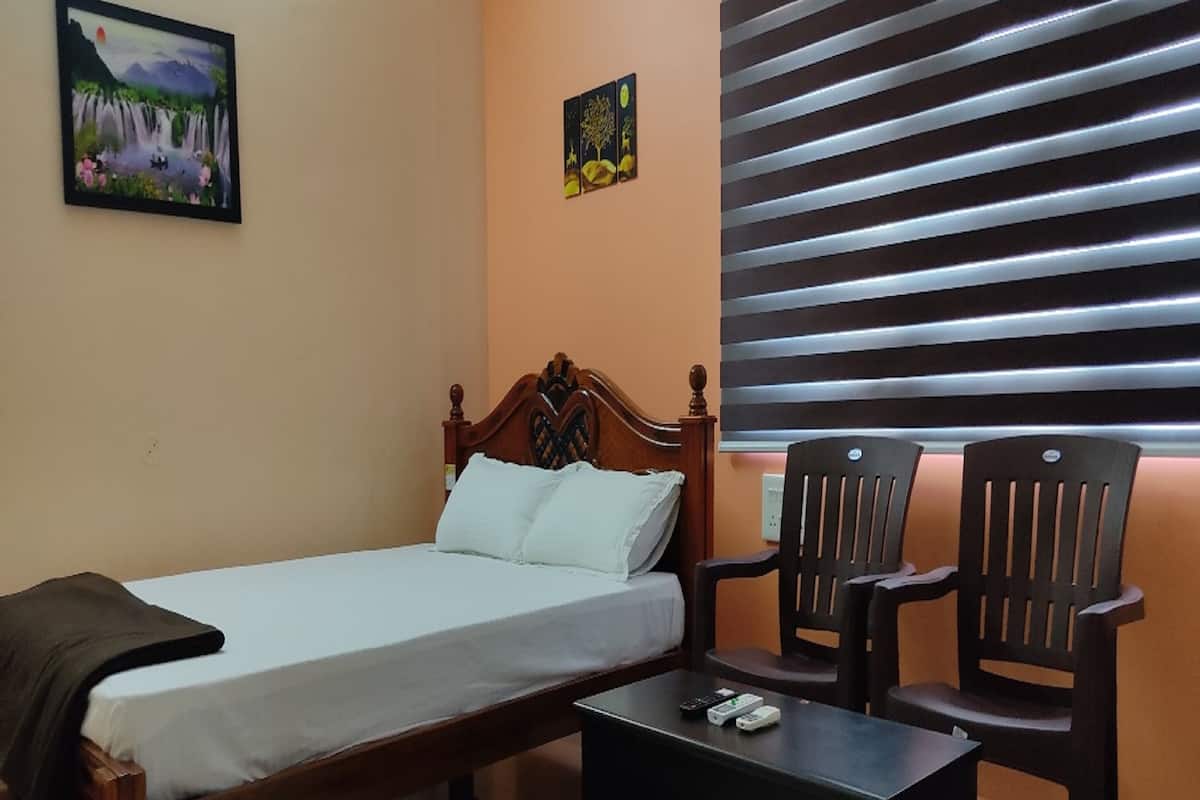A bedroom with a bed, two wooden chairs, a small table, and a painting on the wall.