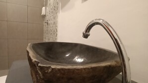 A bathroom with a stone sink, a modern faucet, and a mirror on the wall. - Attara Inn Senggigi (Senggigi)