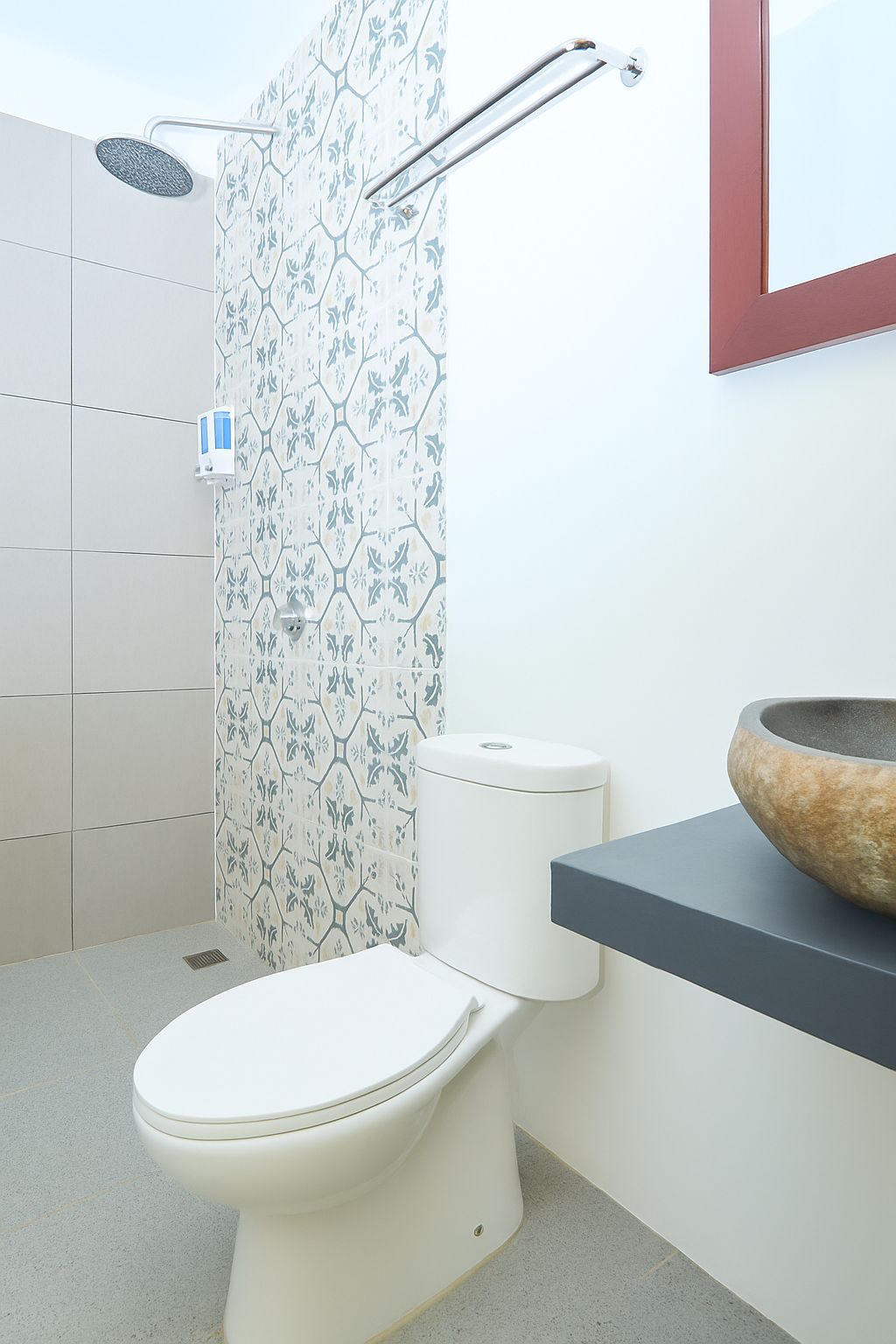 A bathroom with a toilet, a shower, and a sink with a stone basin.